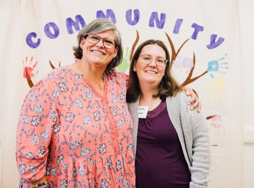 Two women standing in front of a banner that says "Community"