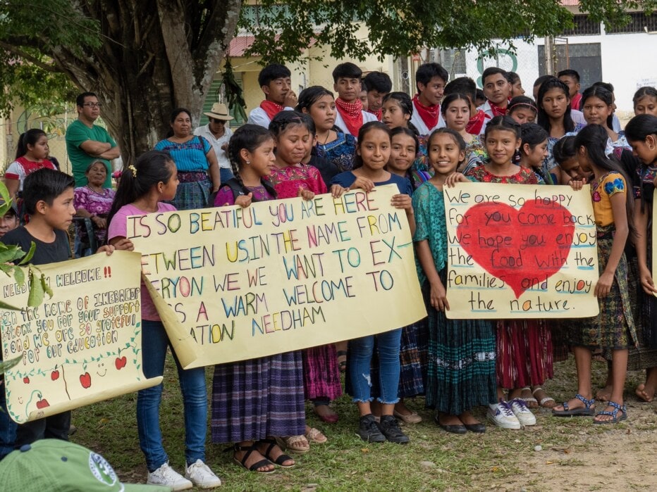 Guatemala villagers hold up welcome signs.